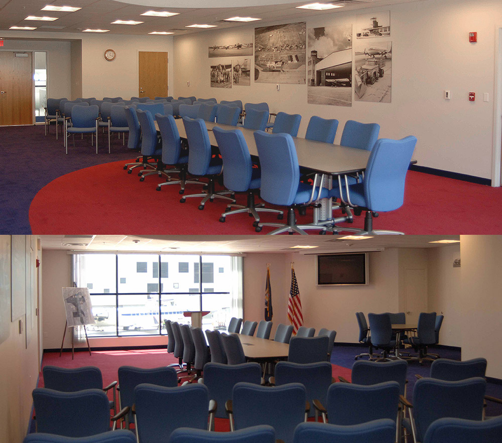 A row of chairs in the front of the room with 14 chairs around a huge conference table at the back of the room. 